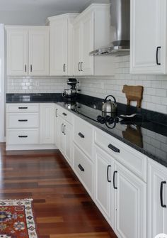 a kitchen with white cabinets and black counter tops