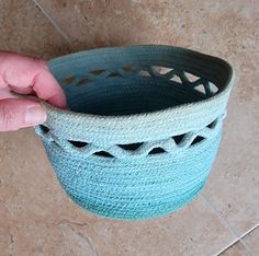 a hand is holding a blue basket on the floor