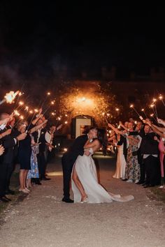 a bride and groom kissing with sparklers in the air at their outdoor wedding reception