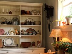 an old fashioned china cabinet with dishes on it's shelves in a living room