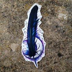 a sticker with a blue feather on it sitting on top of a stone surface