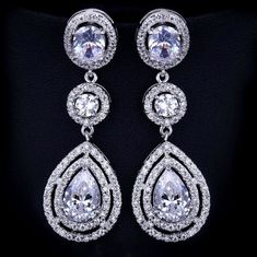 A delightfully unique pair of bridal earrings with an incredible sparkle! Adorned with flawlessly faceted cubic zirconia that capture the light in a dazzling array of sparkles, the earrings are rhodium plated for a bright finish which enhances the intricate detailing and conveys a modern take on old elegance. Overall length of the earring is 52mm (approx. 2"). Hypoallergenic - lead, nickel and cadmium free. This exquisite design will add a touch of sophistication to any wedding gown or formal en Cubic Zirconia Bridal Earrings, Blue Earrings Wedding, Winter Bridal Jewelry, Long Bridal Earrings, Dancing Party, Bridal Accessories Jewelry, Silver Wedding Jewelry, Wedding Earrings Drop, Bridal Fashion Jewelry