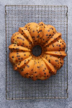 a bundt cake sitting on top of a wire rack next to a gray wall