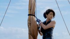 a woman on a boat is holding onto the ropes with one hand and using an air blow dryer