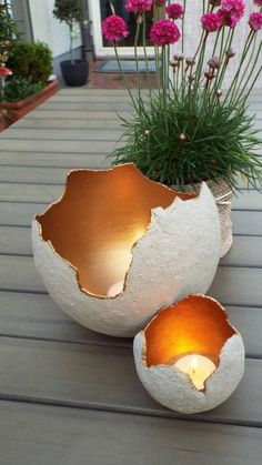 two white vases sitting on top of a wooden table filled with flowers and plants