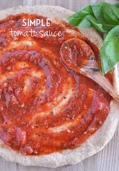 a homemade pizza with sauce and basil leaves on the side, ready to be eaten