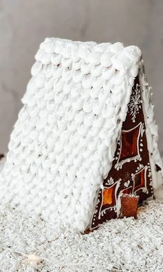 a gingerbread house made out of frosting and icing on top of snow