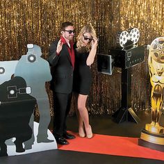 a man and woman standing next to each other in front of an oscars backdrop