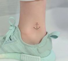 a small anchor tattoo on the foot of a woman's ankle is seen in this image