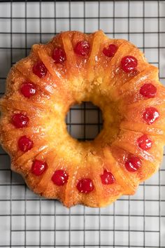 a pineapple bundt cake with cherries on the top is sitting on a cooling rack