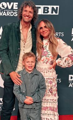 a man and woman standing next to a boy on a red carpet at an awards event