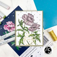 a card with flowers on it next to some crafting supplies and thread spools