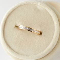 a gold ring with three baguets in it sitting on a white cloth covered box