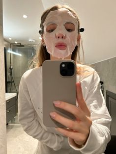 a woman with a face mask on taking a selfie in front of her phone