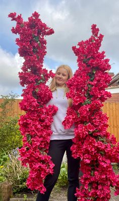 a woman standing in front of some red flowers