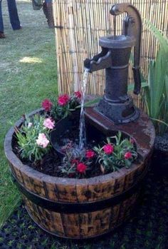 a water fountain in a barrel filled with flowers