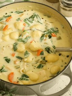 a pot filled with soup and vegetables on top of a stove next to utensils