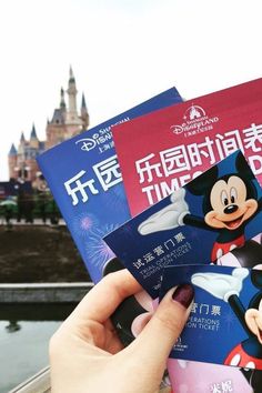 someone is holding three books in front of a castle and some people are looking at them