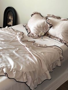 a bed with white sheets and black ruffles on the comforter is shown