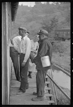 an old black and white photo of three men standing on a bridge with buckets