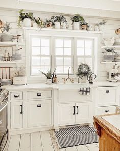 a kitchen filled with lots of white cupboards and counter top covered in pots and pans