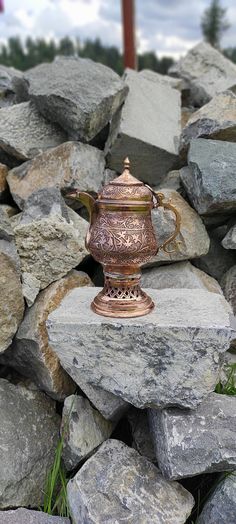 a metal cup sitting on top of a pile of rocks