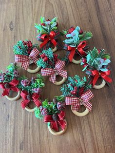 twelve miniature christmas wreaths with bows and pine cones on wooden wheels sitting on a table