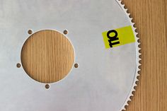 a close up of a metal object on a wooden surface with a yellow sticker