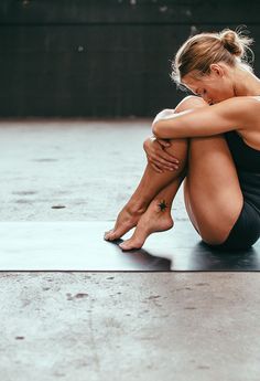 a woman sitting on the ground with her arms crossed and legs crossed, in front of an instagram page