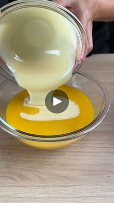 a person pouring milk into a bowl on top of a wooden table