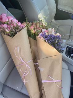 two brown paper bags with pink roses tied to them sitting in the back seat of a car