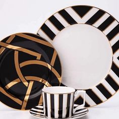 a black and white plate with gold lines on it, next to a cup and saucer