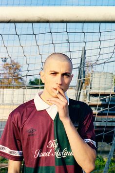 a young man standing in front of a soccer net with his finger to his mouth