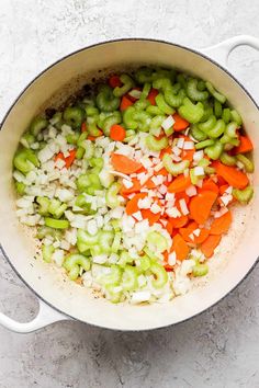 vegetables are mixed together in a pot on the counter top, including carrots and celery