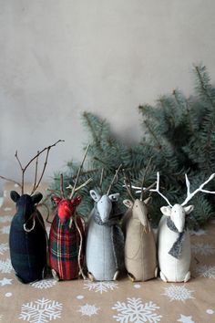 four small stuffed animals are lined up next to a christmas tree with snowflakes on it