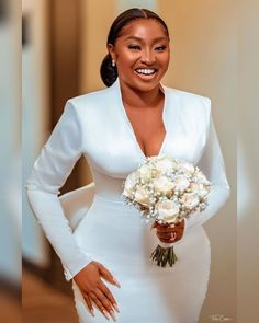 a woman in a white dress holding a bouquet of flowers and smiling at the camera