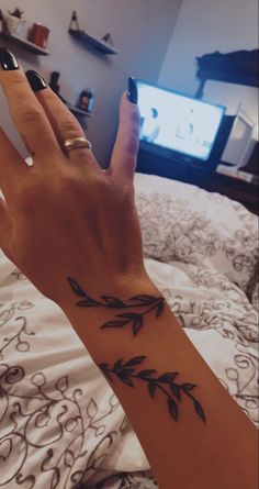 a woman's hand with an arrow tattoo on her left wrist and the other arm