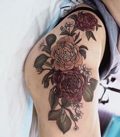 a woman's arm with flowers on it and leaves around the arm, in front of her