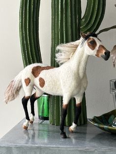 a toy horse standing on top of a table next to a cactus