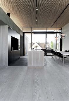 an open kitchen and dining room area with wood flooring, white walls and ceiling