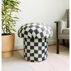 a black and white checkered ottoman next to a potted plant