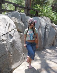 a girl with pig ears is walking by some large rocks and holding her hand on her hip