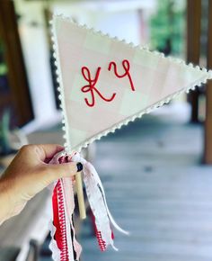 a person holding up a small flag with the letter k on it