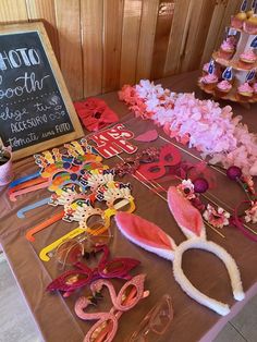 a table topped with lots of pink and white decorations next to a chalkboard sign