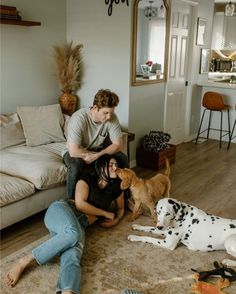 a man and woman sitting on the floor with two dogs