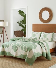 a bed with green and white bedspread in a bedroom next to a mirror