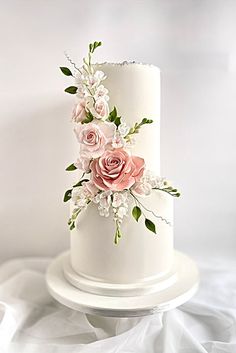 a white wedding cake with pink flowers and greenery