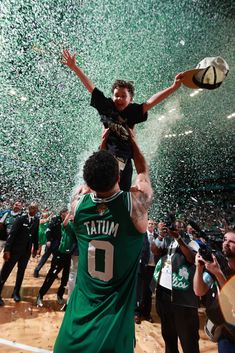 a man holding a young child in his arms as confetti is thrown around him