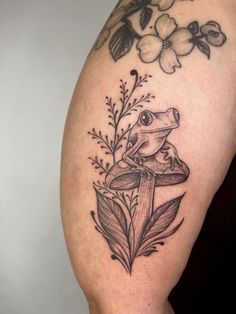 a frog sitting on top of a mushroom with flowers around it's neck and legs