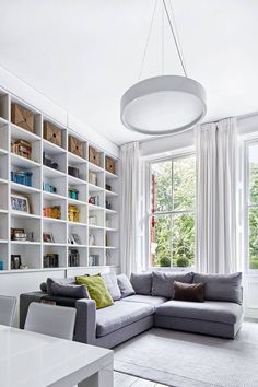 a living room filled with furniture and lots of bookshelves next to a window